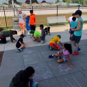ICE Program mentors with kids drawing on sidewalk