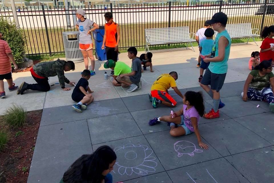 ICE Program mentors with kids drawing on sidewalk