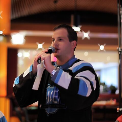 Photo of Josh Klein speaking on microphone at fundraiser