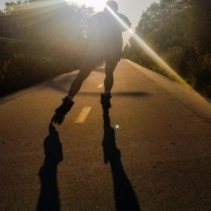 Brad Erickson skating down a bike path with sun in background