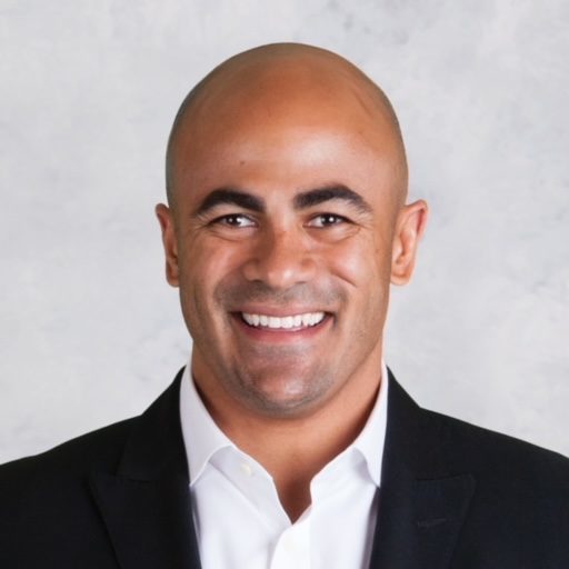 Portrait photo of Jamal Mayers smiling and wearing a suit